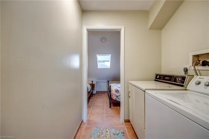 Washroom featuring light tile patterned floors, laundry area, baseboards, and washer and dryer