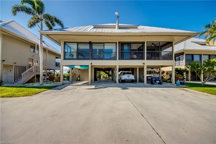 View of building exterior with stairs, a carport, and concrete driveway