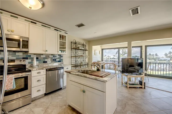Kitchen with visible vents, appliances with stainless steel finishes, decorative backsplash, and a sink