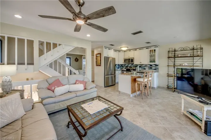 Living room featuring light tile patterned floors, recessed lighting, visible vents, a ceiling fan, and stairs
