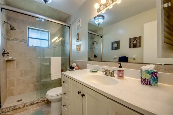 Full bathroom with toilet, a stall shower, and vanity