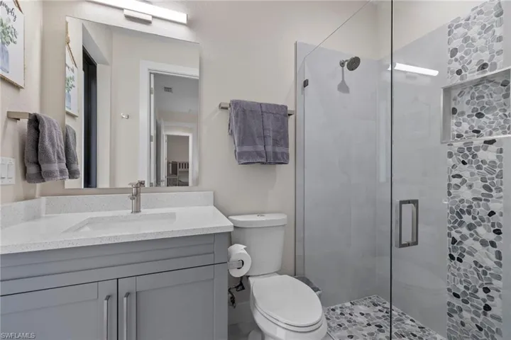 Bathroom featuring an enclosed shower, toilet, and vanity