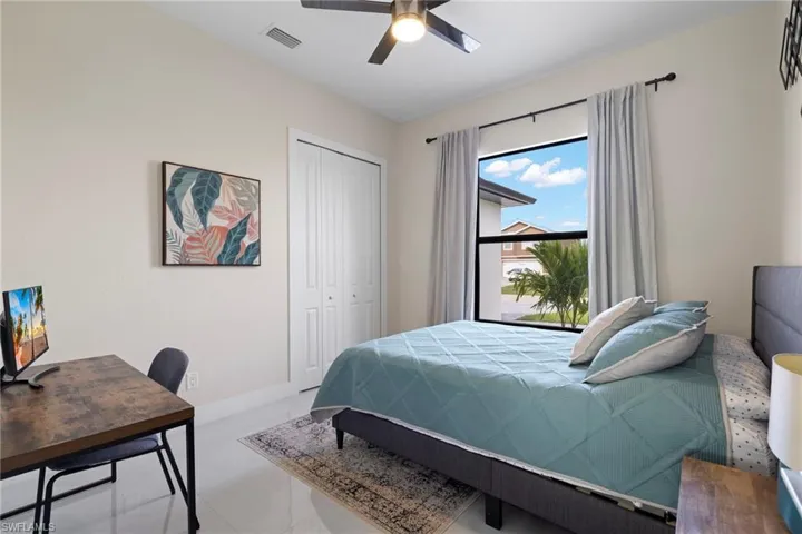 Tiled bedroom featuring ceiling fan and a closet
