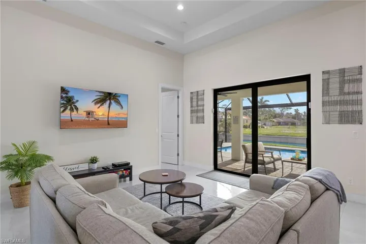 Living room featuring a raised ceiling, a high ceiling, and light tile patterned floors
