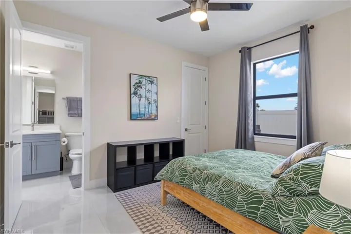 Bedroom featuring ceiling fan, connected bathroom, sink, and light tile patterned floors