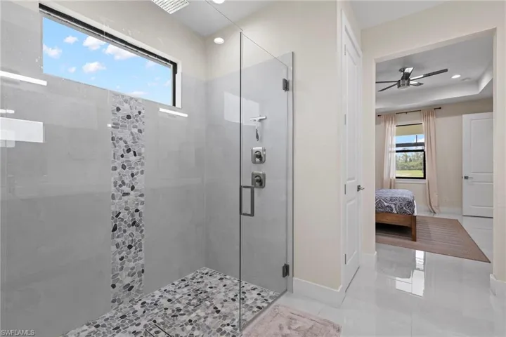 Bathroom with ceiling fan, an enclosed shower, and tile patterned flooring