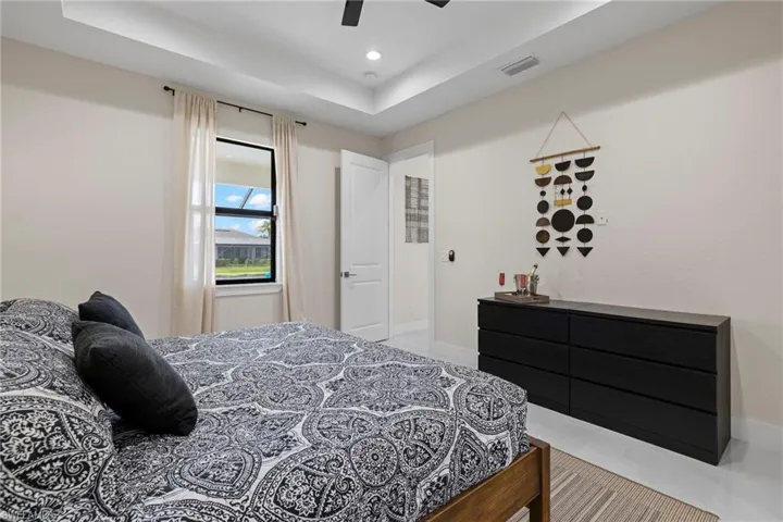 Tiled bedroom with ceiling fan and a tray ceiling
