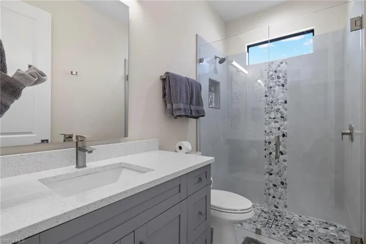 Bathroom featuring vanity, walk in shower, and toilet