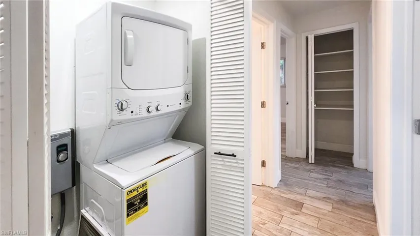 Laundry area featuring light wood-style flooring and stacked washing machine and dryer