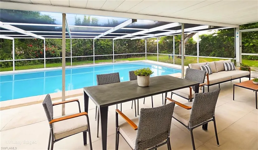 Swimming pool featuring outdoor seating, glass enclosure, a patio area, a yard, and a sunroom