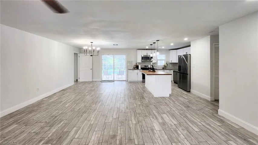 Kitchen featuring white cabinets, stainless steel appliances, wood tiled floors, a kitchen island, and wooden counters