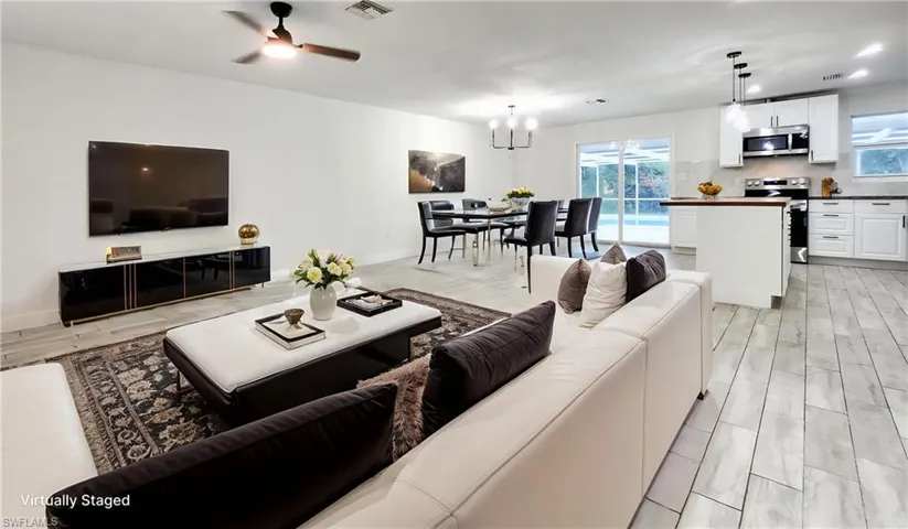 Living room featuring ceiling fan, wood finish floors, suspended lighting, and plenty of natural light