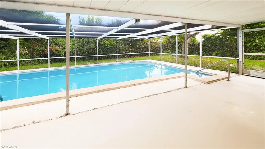View of pool with glass enclosure and patio surround