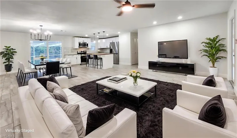 Living room featuring a ceiling fan, light wood-style flooring, and suspended lighting