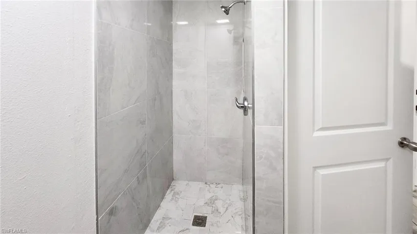 Full bath with a shower stall and a textured wall
