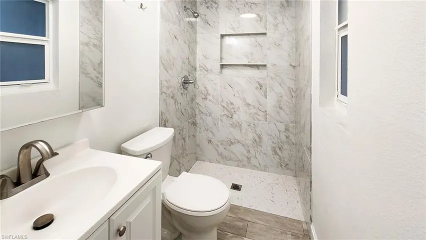 Bathroom with vanity, a marble finish shower, and a textured wall