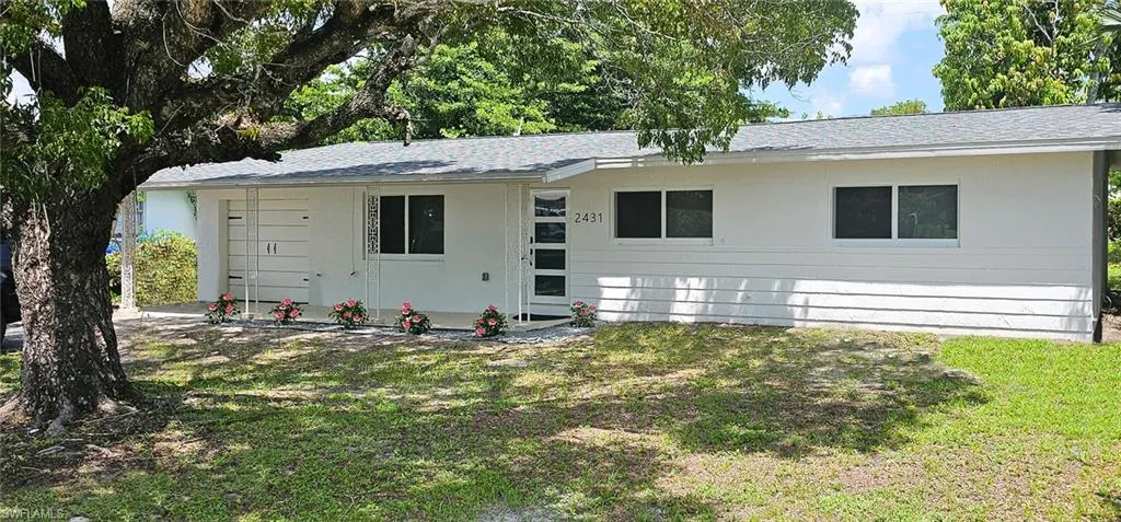 View of front facade featuring a front yard and a shingled roof