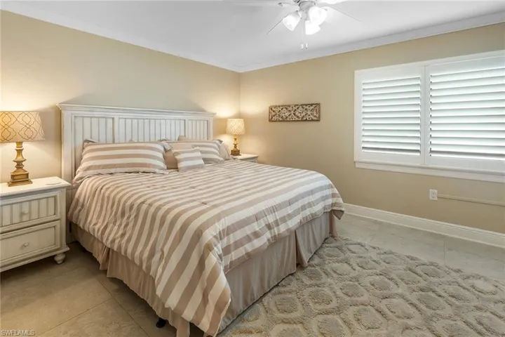 Bedroom with light tile patterned floors, crown molding, baseboards, and a ceiling fan