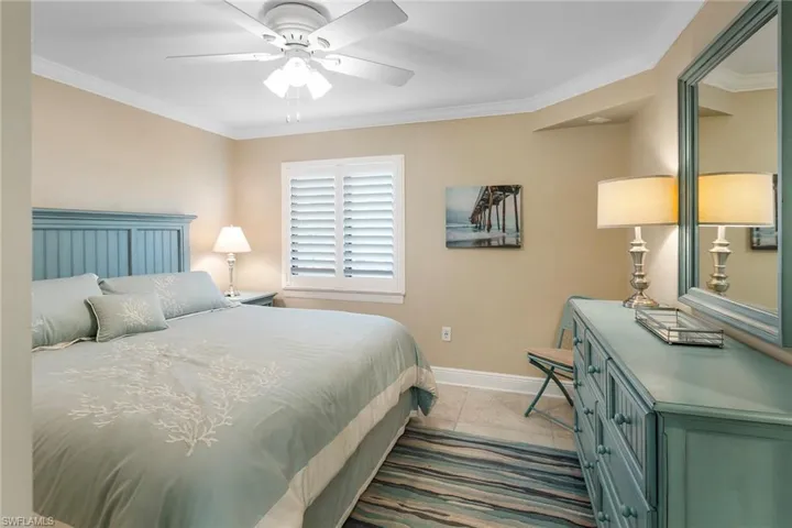 Tiled bedroom with baseboards, ornamental molding, and ceiling fan