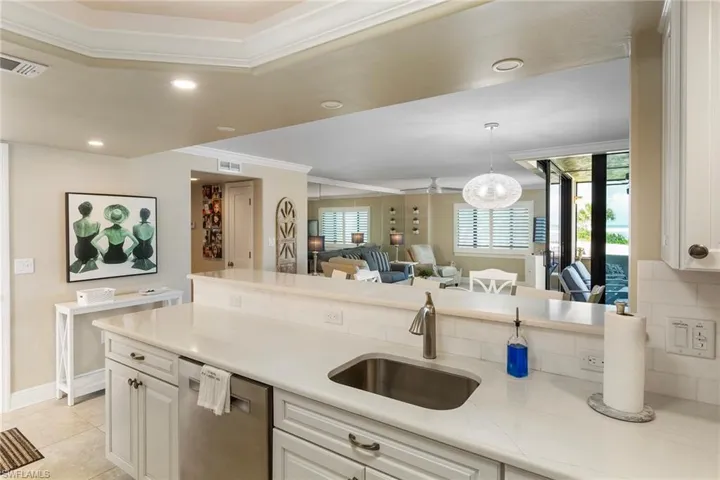 Kitchen with crown molding, a sink, stainless steel dishwasher, light countertops, and open floor plan