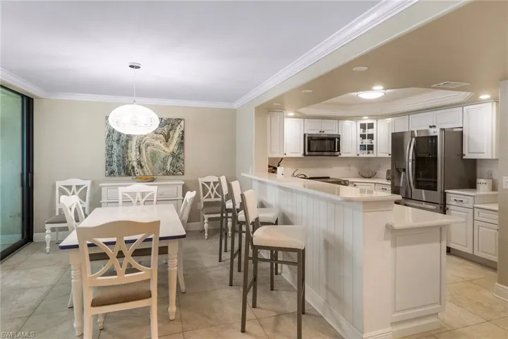Kitchen featuring appliances with stainless steel finishes, decorative backsplash, light countertops, crown molding, and white cabinetry