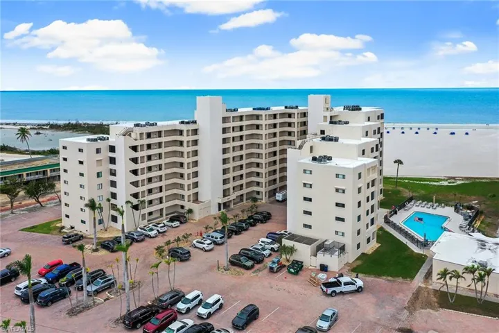 Drone / aerial view of apartment complex, a nearby body of water, and a pool