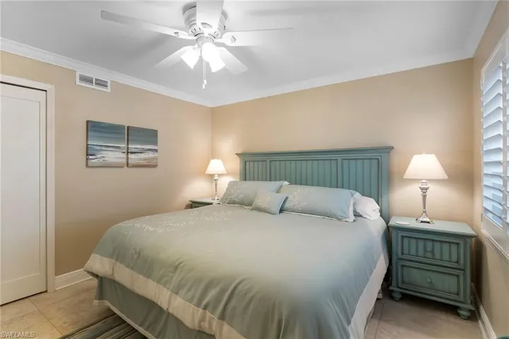 Bedroom featuring light tile patterned flooring, crown molding, baseboards, and ceiling fan