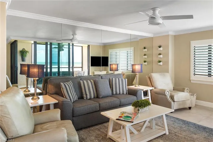 Tiled living room with a ceiling fan, healthy amount of natural light, crown molding, and baseboards
