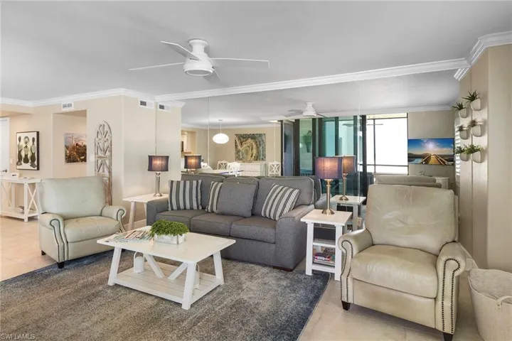 Living room featuring ceiling fan, tile patterned floors, and ornamental molding