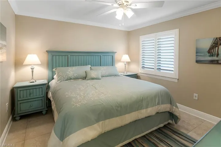 Tiled bedroom featuring baseboards, crown molding, and ceiling fan