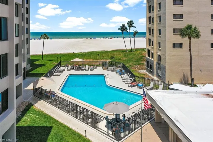 Community pool with a patio and view of water and beach