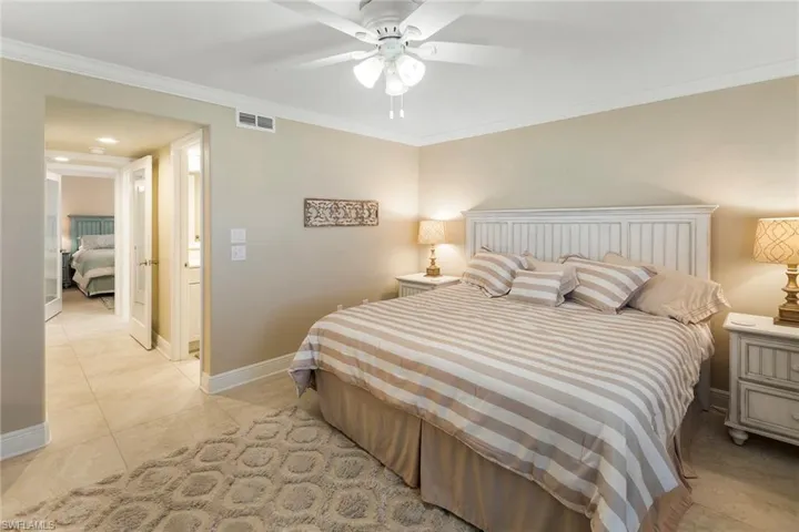 Bedroom featuring baseboards, crown molding, light tile patterned floors, and a ceiling fan