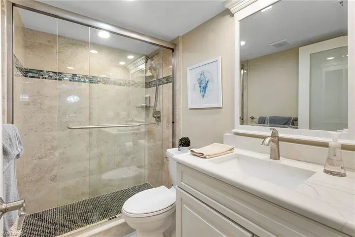 Bathroom with toilet, a shower stall, vanity, and recessed lighting