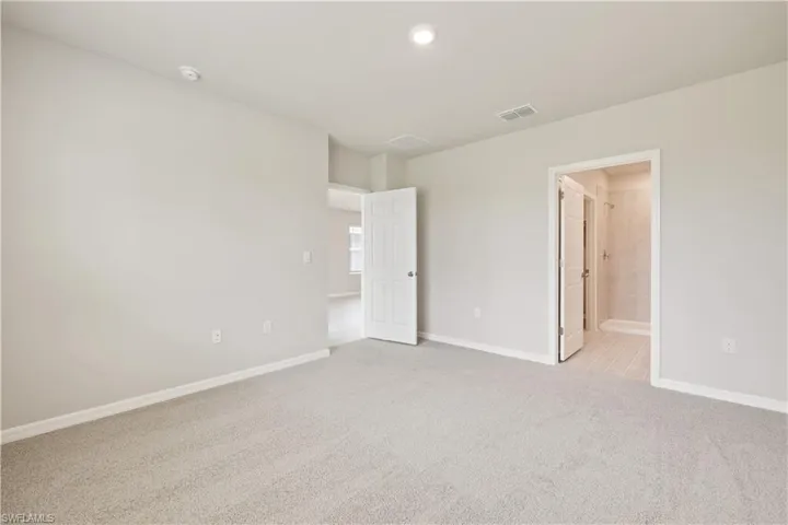 Unfurnished bedroom featuring connected bathroom and light colored carpet