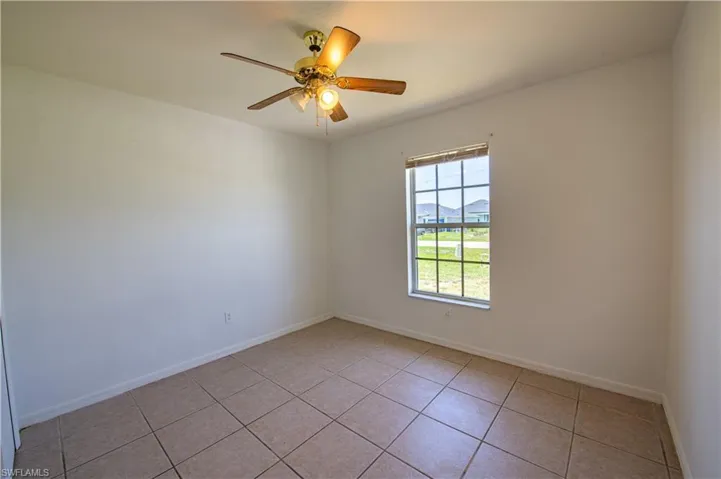 Interior room featuring a ceiling fan with light fixture, tiled flooring, and a window with blinds