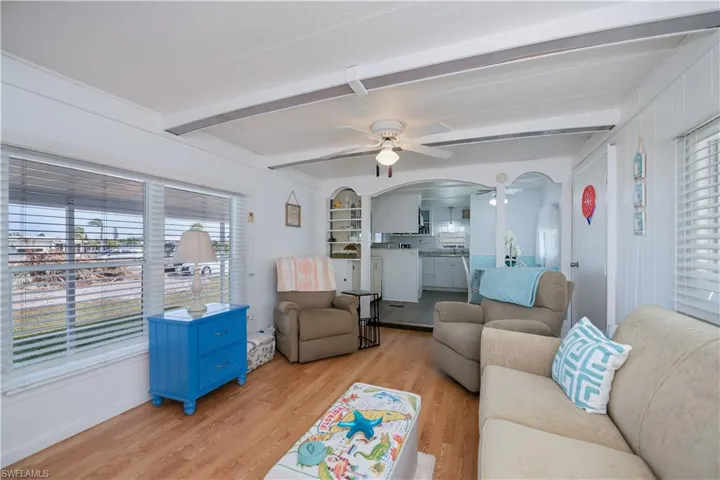 Living room featuring beam ceiling, light wood-type flooring, and ceiling fan