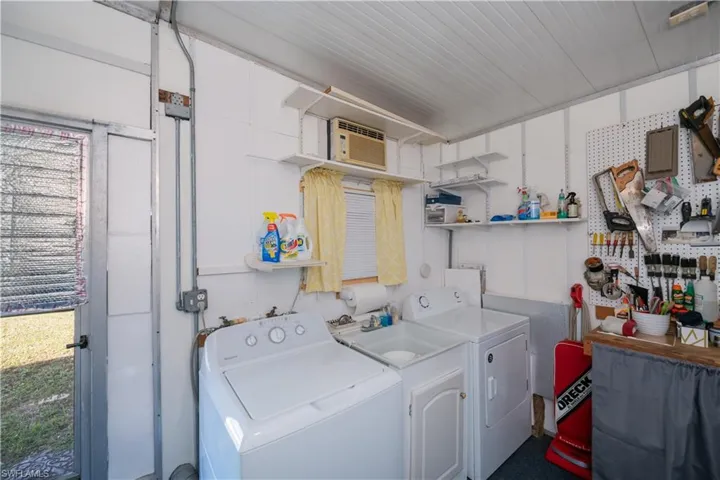 Washroom featuring a wall mounted AC and washer and dryer and utility sink