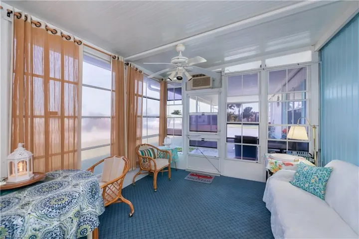 Sunroom / solarium featuring a wall unit AC and ceiling fan