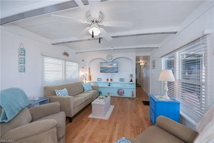 Living room with beam ceiling, light hardwood / wood-style flooring, and ceiling fan