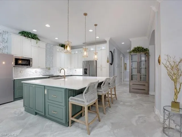 Gourmet kitchen featuring a large central island with seating, white shaker cabinetry, a mosaic tile backsplash, stainless steel appliances, and wood-finish flooring