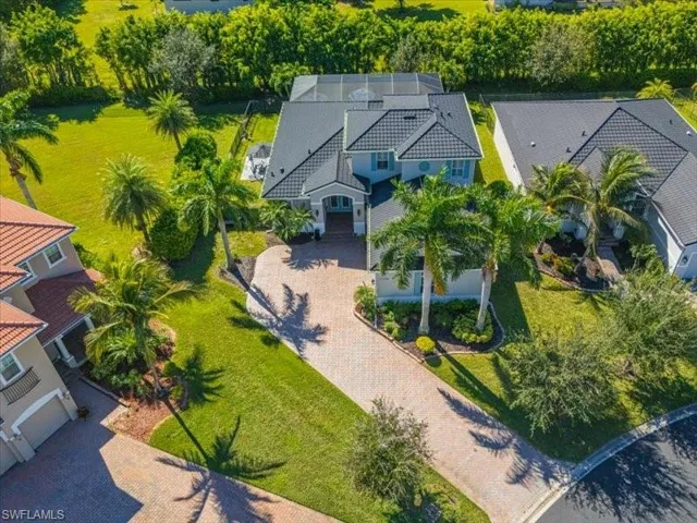 Expansive residential property featuring a large paver driveway, mature palm trees, and manicured lawns