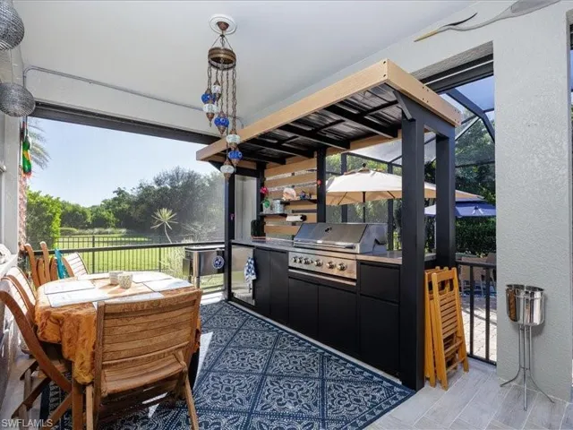 Screened lanai featuring a built-in outdoor kitchen with a gas grill and integrated cabinetry