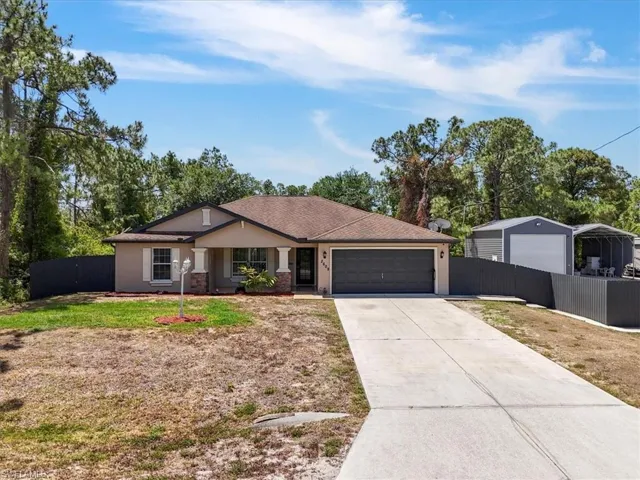Ranch-style home with driveway, stucco siding, a front yard, an attached garage, and fence