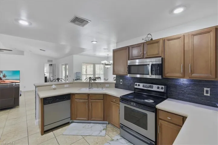 Kitchen with a peninsula, stainless steel appliances, light countertops, a sink, and open floor plan