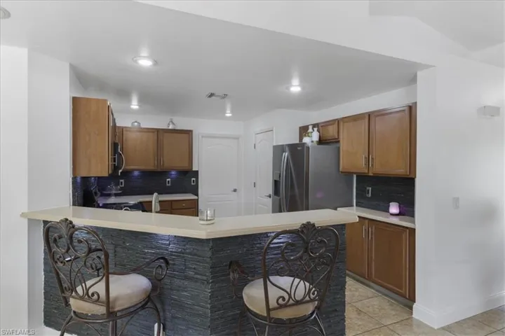 Kitchen featuring appliances with stainless steel finishes, light countertops, backsplash, visible vents, and light tile patterned flooring