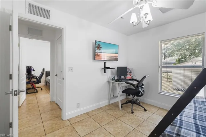 Office area featuring visible vents, light tile patterned floors, and a notable chandelier