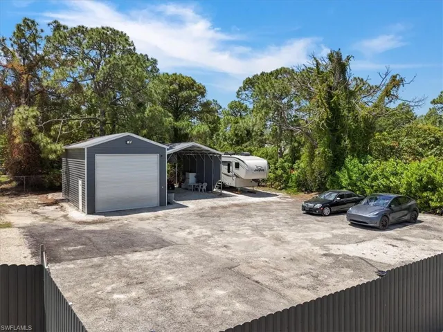 View of parking / parking lot with fence and a garage