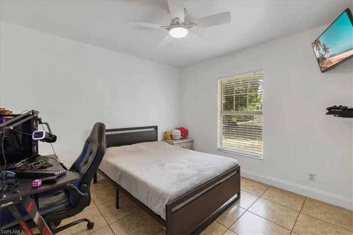 Bedroom with ceiling fan, tile patterned flooring, and baseboards