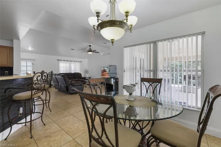 Dining room with light tile patterned floors and ceiling fan with notable chandelier