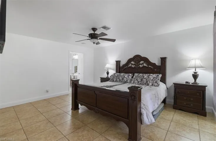 Bedroom featuring light tile patterned floors, visible vents, ceiling fan, and baseboards